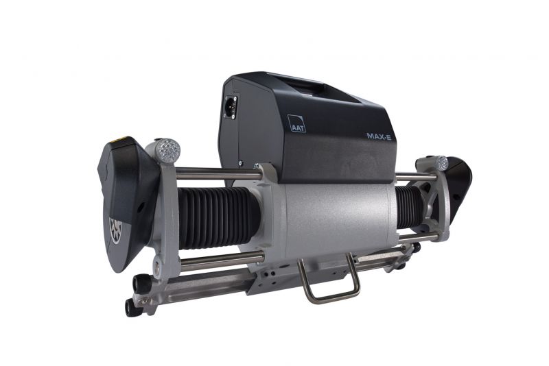 The picture shows the drive unit of the MAX-E electric add-on drive. The black and silver design of the drive unit can be seen, as well as both drive shafts, which power the wheelchair via toothed rims that are attached to the wheelchair wheels.