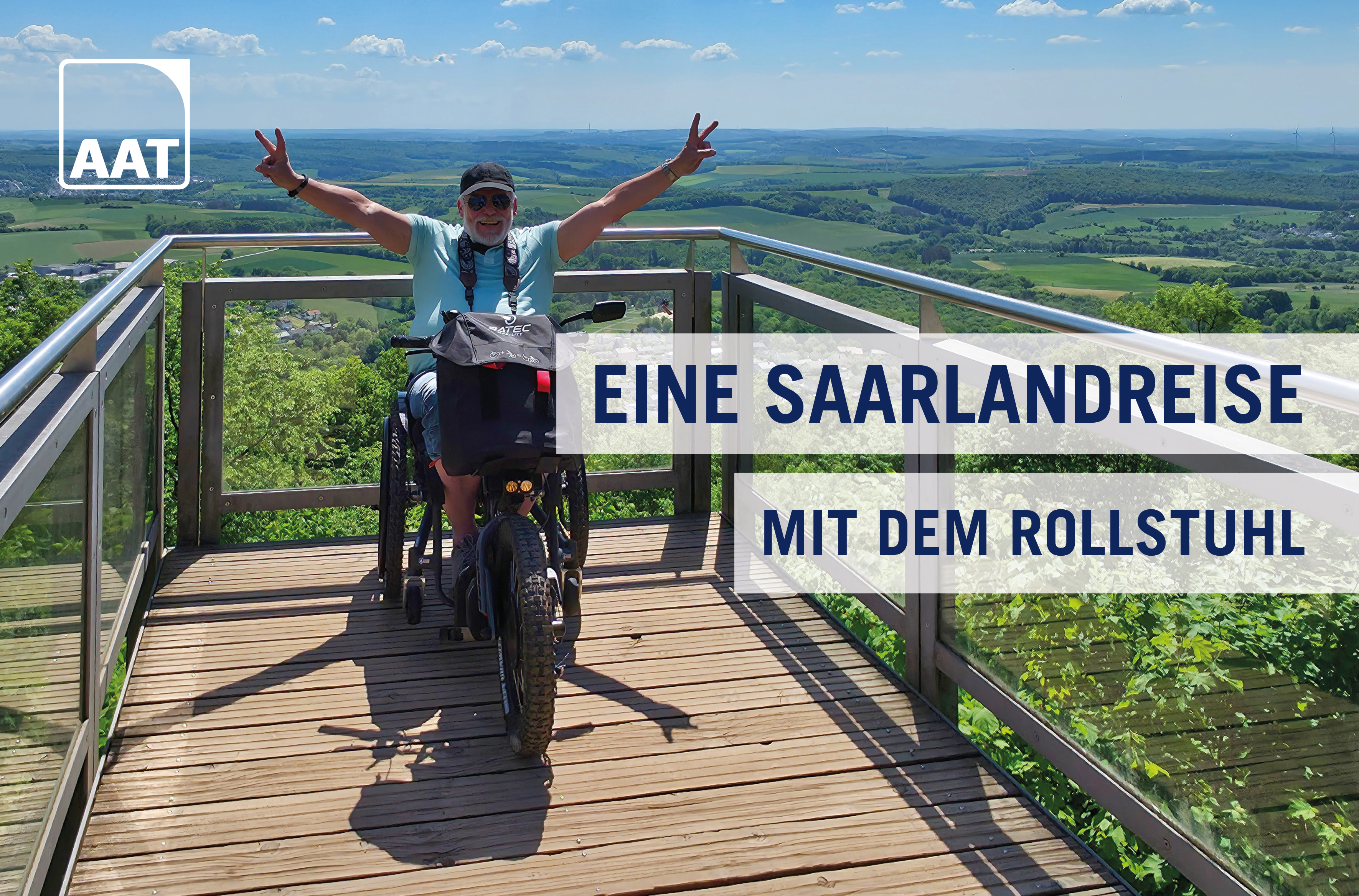 Auf dem Bild ist Hans-Jürgen Rohe zu sehen, wie er mit seinem Rollstuhl und Rollstuhlzuggerät SCRAMBLER 2 von BATEC und AAT auf einer Aussichtsplattform über dem Saarland steht. Er streckt seine Hände in die Luft und zeigt zwei Peace-Zeichen mit den Fingern.