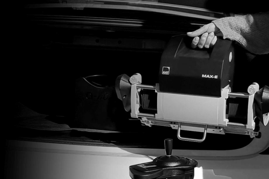 Auf dem Bild ist der Ausschnitt eines PKW-Kofferraumes zu sehen. Eine Frauenhand hebt die Antriebseinheit problemlos und mit einer Hand in den Kofferraum. 