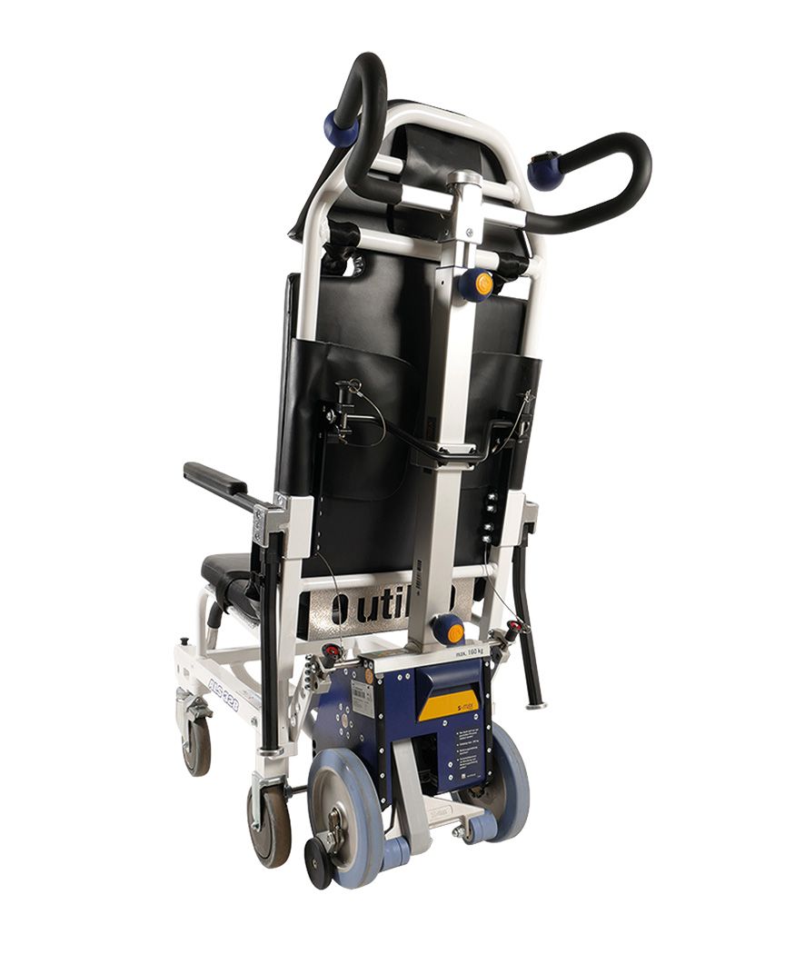 Das Bild zeigt die freigestellte Antriebs- und Griffeinheit des Treppensteiger s-max sella auf weißem Hintergrund. Sichtbar ist die graue Antriebseinheit mit Laufrädern und Sicherheitsbremsen, sowie die Griffeinheit mit Bedienteil. Der Treppensteiger ist über eine Halterung an einem Tragestuhl – hier im Beispiel ein Utila ALS 328 – angebaut. 